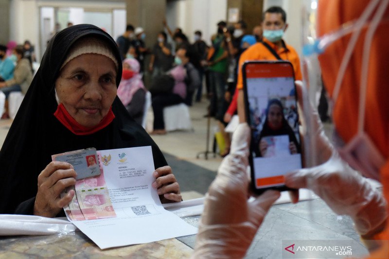 Petugas PT Pos Indonesia memotret wajah warga penerima Bantuan Sosial Tunai (BST) tahap VIII untuk kelengkapan administrasi pada proses penyaluran BST di Medan, Sumatera Utara, Jumat (13/11/2020). ANTARA FOTO/Irsan Mulyadi/Lmo/foc.
