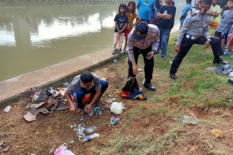 Petugas kepolisian menyisir bantaran Kalimalang untuk mengumpulkan barang bukti berupa tas berisi sendok makan milik korban kecelakaan minibus yang terjun ke Kalimalang, Sumber Artha, Kota Bekasi, Jumat (10/7/2020). (ANTARA/Andi Firdaus).