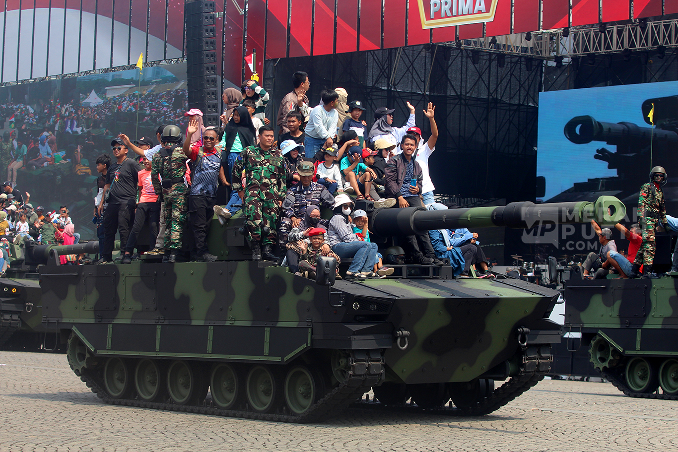 Wajah bahagia warga naik Tank Lapis Baja dalam parade defile alat utama sistem senjata (alutsista) milik TNI dalam peringatan Hari Ulang Tahun (HUT) ke-79 TNI di Lapangan Silang Monas, Jakarta Pusat, Sabtu (5/10/2024).
