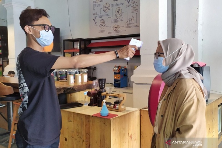 Pengunjung dicek suhu tubuhnya saat memasuki kafe yang berada di Jalan Braga, Kota Bandung, Jawa Barat, Sabtu (12/12/2020). (ANTARA/Bagus Ahmad Rizaldi)