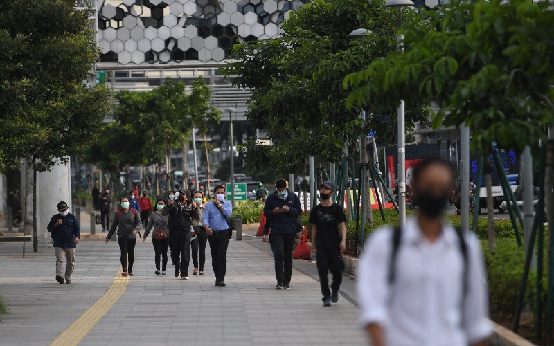 Sejumlah pekerja berjalan usai bekerja dengan latar belakang gedung perkantoran di Jl. Jenderal Sudirman, Jakarta, Kamis (16/4/2020). Pemprov DKI Jakarta akan memberikan sanksi berupa mencabut perizinan kepada perusahaan yang tetap beroperasi di masa Pembatasan Sosial Berskala Besar (PSBB) kecuali delapan sektor yang memang diizinkan. - ANTARA FOTO/Akbar Nugroho Gumay