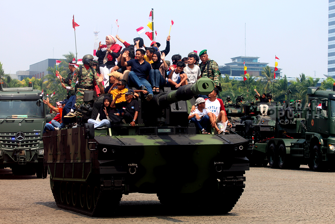 Wajah bahagia warga naik Tank Lapis Baja dalam parade defile alat utama sistem senjata (alutsista) milik TNI dalam peringatan Hari Ulang Tahun (HUT) ke-79 TNI di Lapangan Silang Monas, Jakarta Pusat, Sabtu (5/10/2024).
